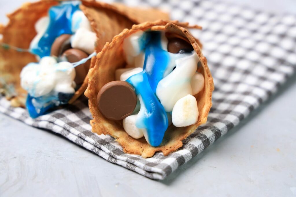 Shark campfire cones are loaded with marshmallows, Hershey's kisses, and shark gummy candies in a waffle cone.