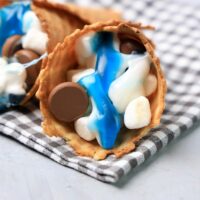Shark campfire cones are loaded with marshmallows, Hershey's kisses, and shark gummy candies in a waffle cone.