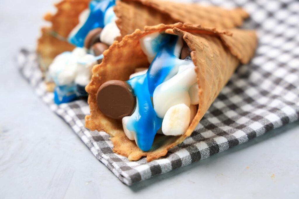 Shark campfire cones are loaded with marshmallows, Hershey's kisses, and shark gummy candies in a waffle cone.