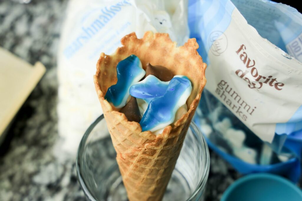Waffle cone filled with chocolate, gummy sharks, and marshmallows.