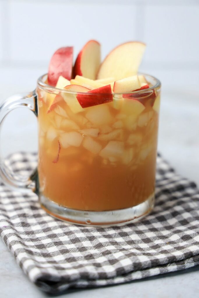Apple Cider Rum Cocktail in a short, clear glass with fresh apples.