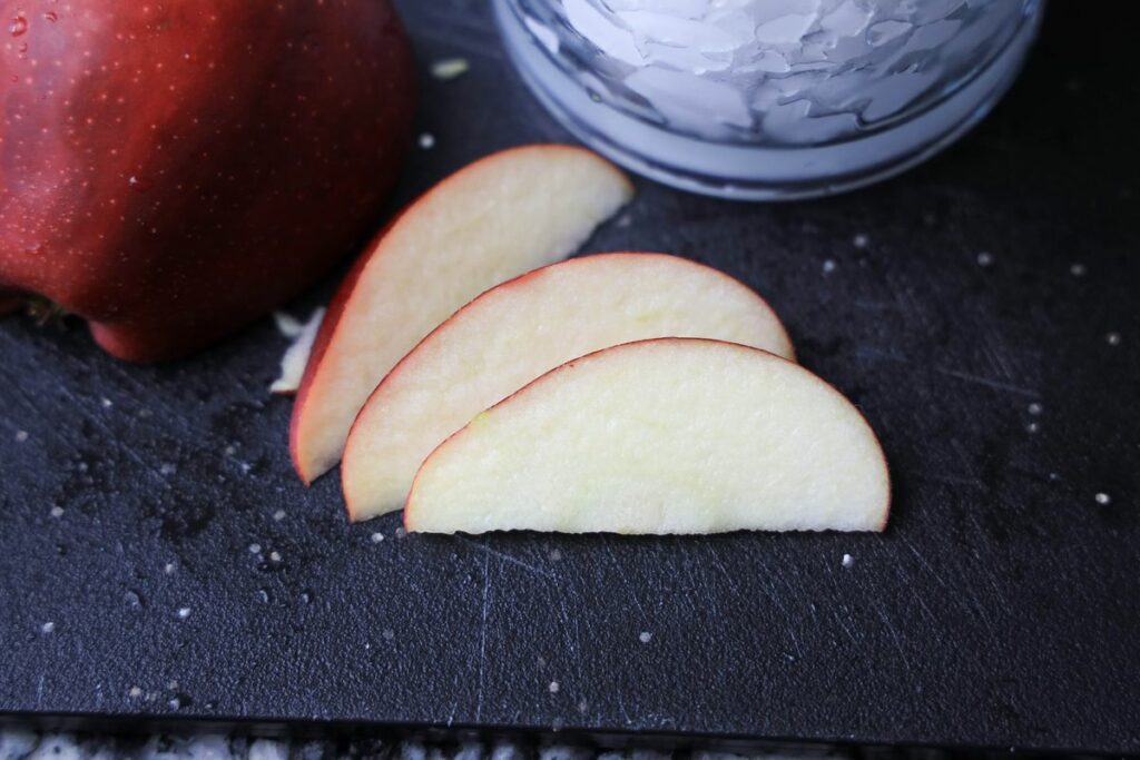 Sliced red apples on a black cutting board.