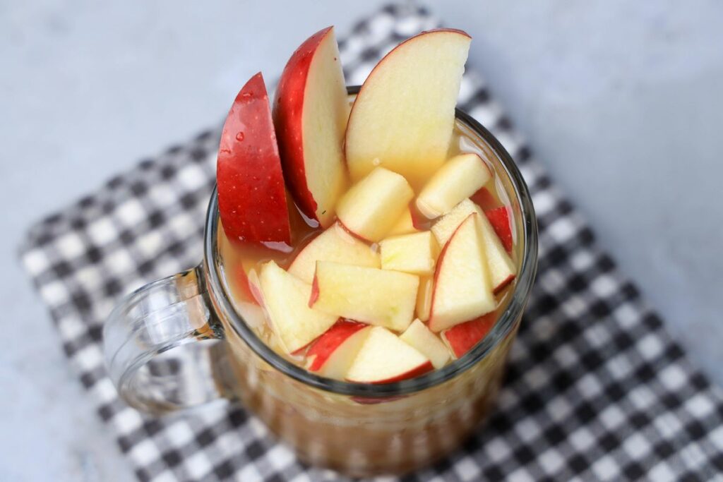 Apple Cider Rum Cocktail in a short, clear glass with fresh apples.