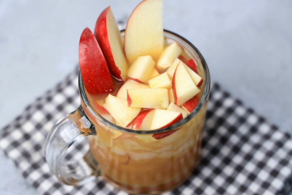 Apple Cider Rum Cocktail in a short, clear glass with fresh apples.