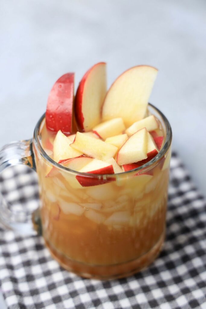 Apple Cider Rum Cocktail in a short, clear glass with fresh apples.