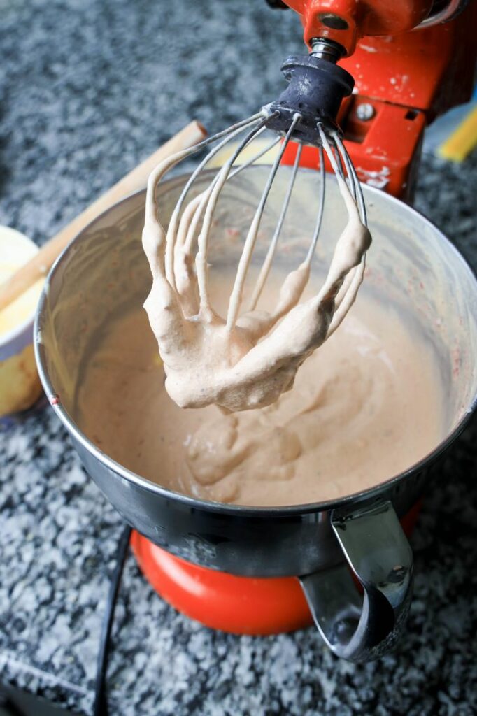 Cranberry sauce and vanilla ice cream inside the bowl of a stand mixer.