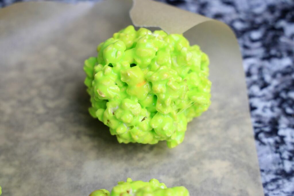 Green popcorn ball on parchment paper.
