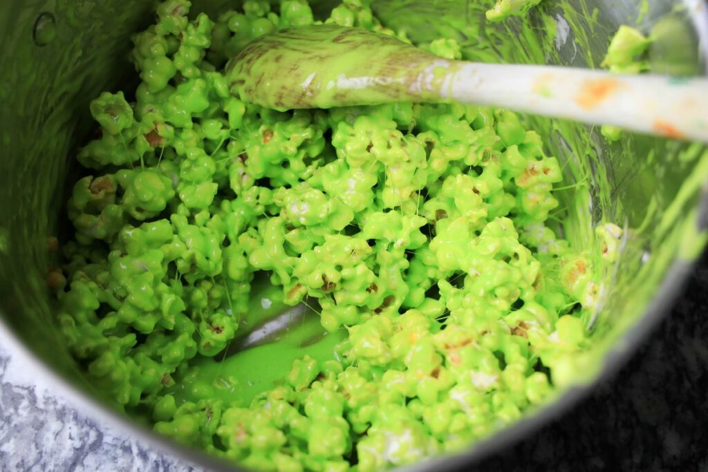 Green popcorn in a pot when coating it with a marshmallow mixture.