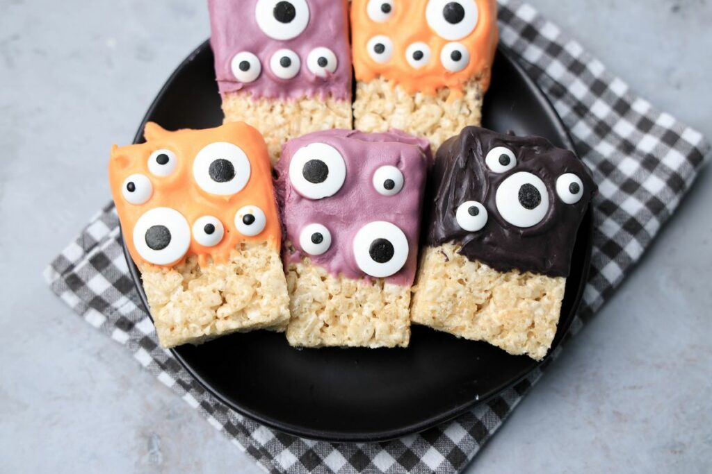 Monster Rice Krispies Treats on a black plate with a gray plaid napkin.