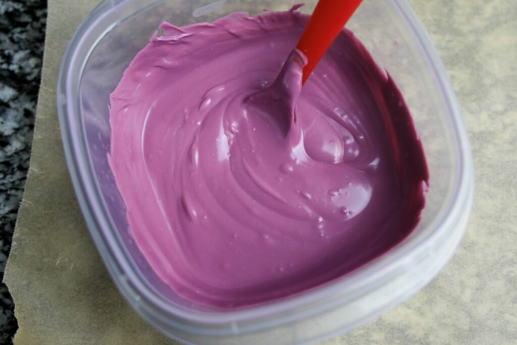 Purple candy melts in a microwave safe bowl.