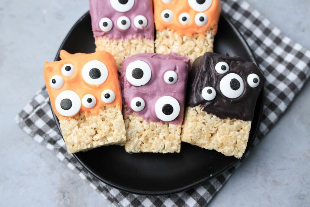 Monster Rice Krispies Treats on a black plate with a gray plaid napkin.