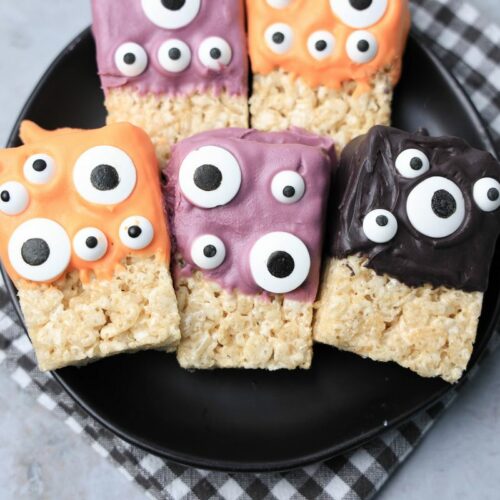 Monster Rice Krispies Treats on a black plate with a gray plaid napkin.