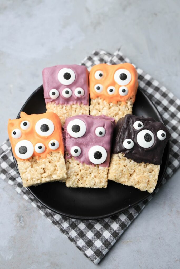 Monster Rice Krispies Treats on a black plate with a gray plaid napkin.