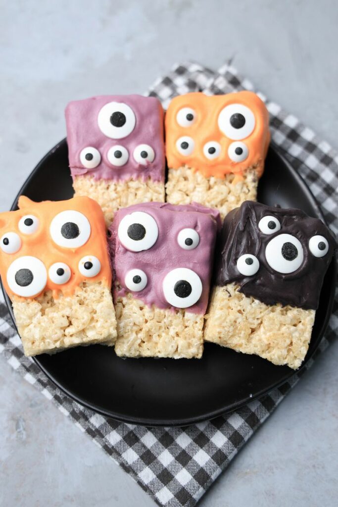 Monster Rice Krispies Treats on a black plate with a gray plaid napkin.